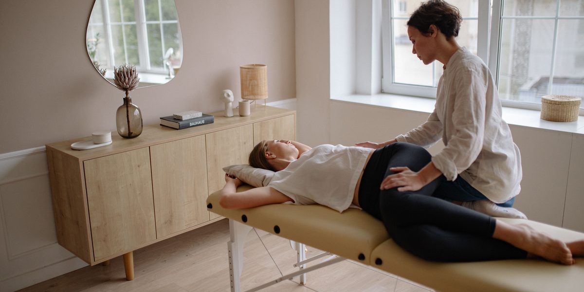 A chiropractor treating a patient on the table in a calm, bright treatment room.