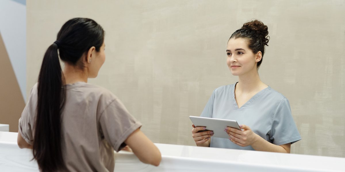 A front desk team member checking a patient in at the counter.